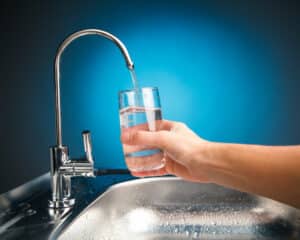 hand pouring a glass of water from a reverse osmosis filter tap