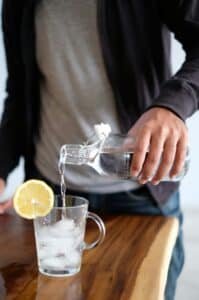 someone pouring reverse osmosis water from a bottle into a glass